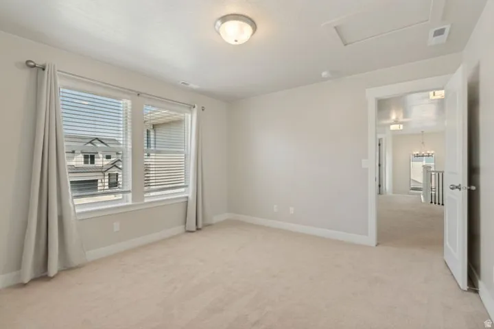 Carpeted room featuring a double window with blinds and drapes, an overhead flush-mount light fixture, and white baseboards