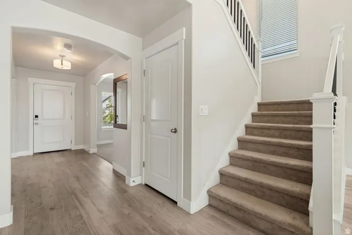 Entryway featuring wood-finish flooring, an arched doorway, and a contemporary flush-mount light fixture
