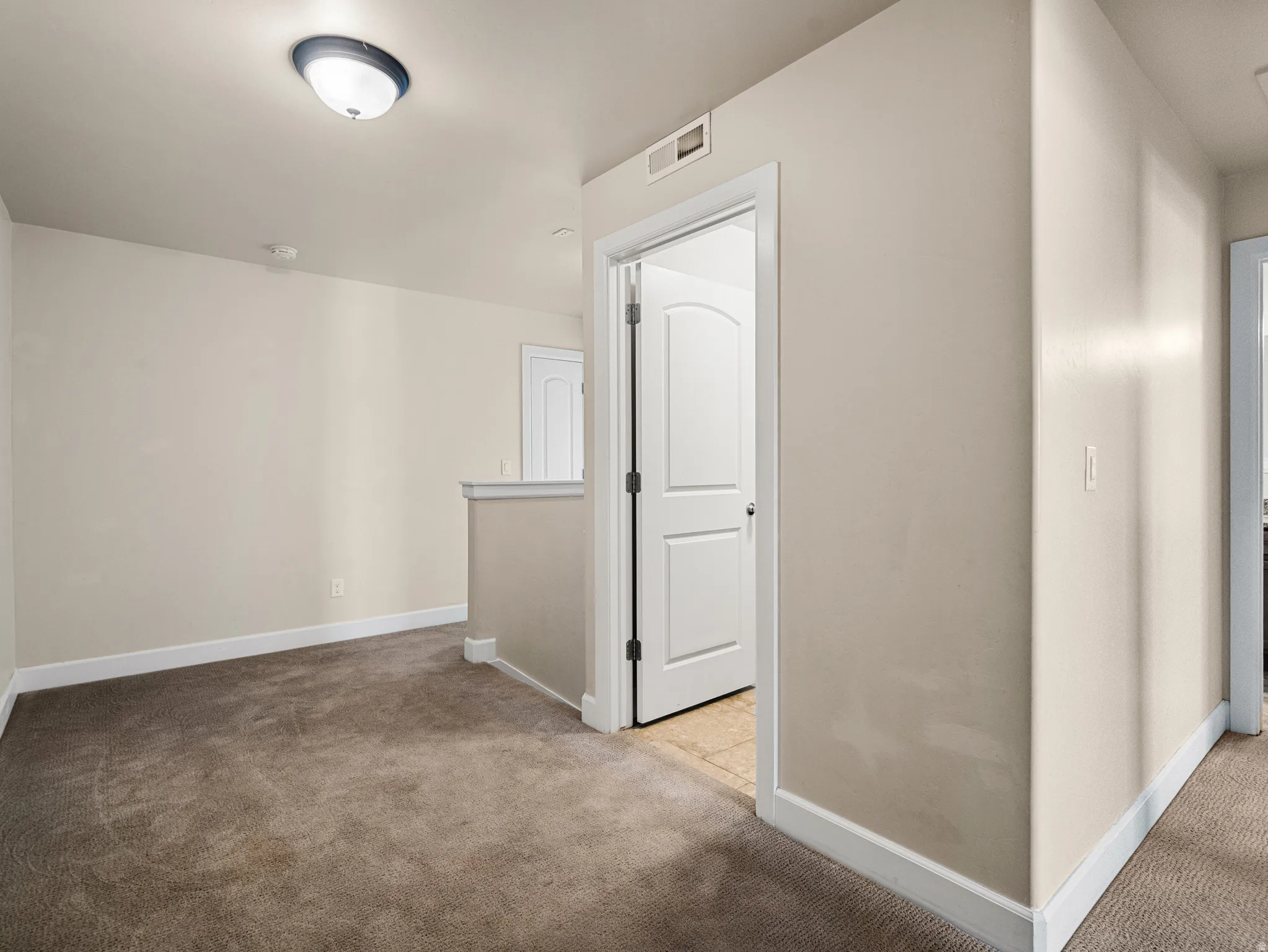Neutral wall tones complement plush carpeting, creating a comfortable area