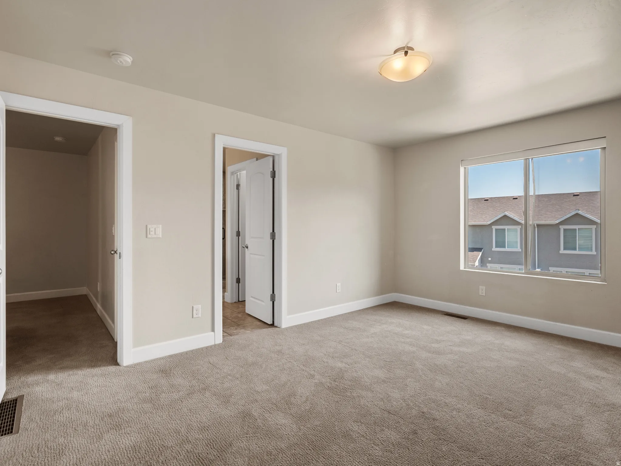 Spacious room featuring neutral carpeting, a large window, and light-toned walls