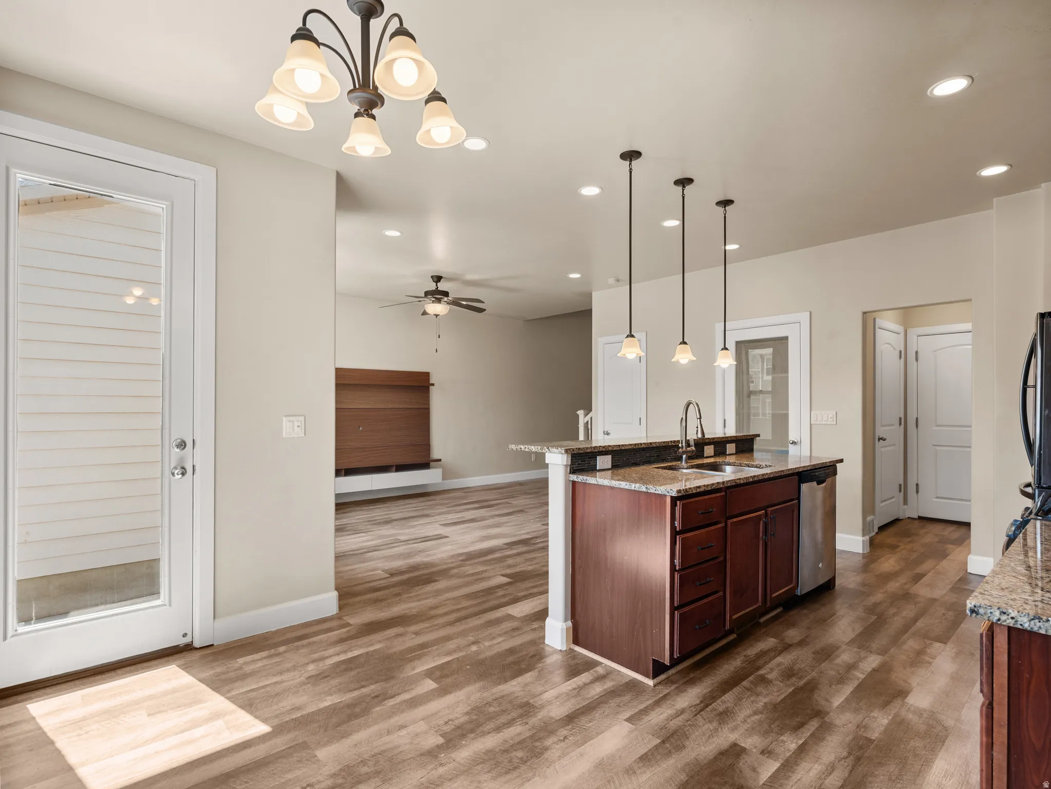 Spacious open-concept kitchen and living area featuring a custom island with rich wood cabinetry, black countertops, and pendant lighting