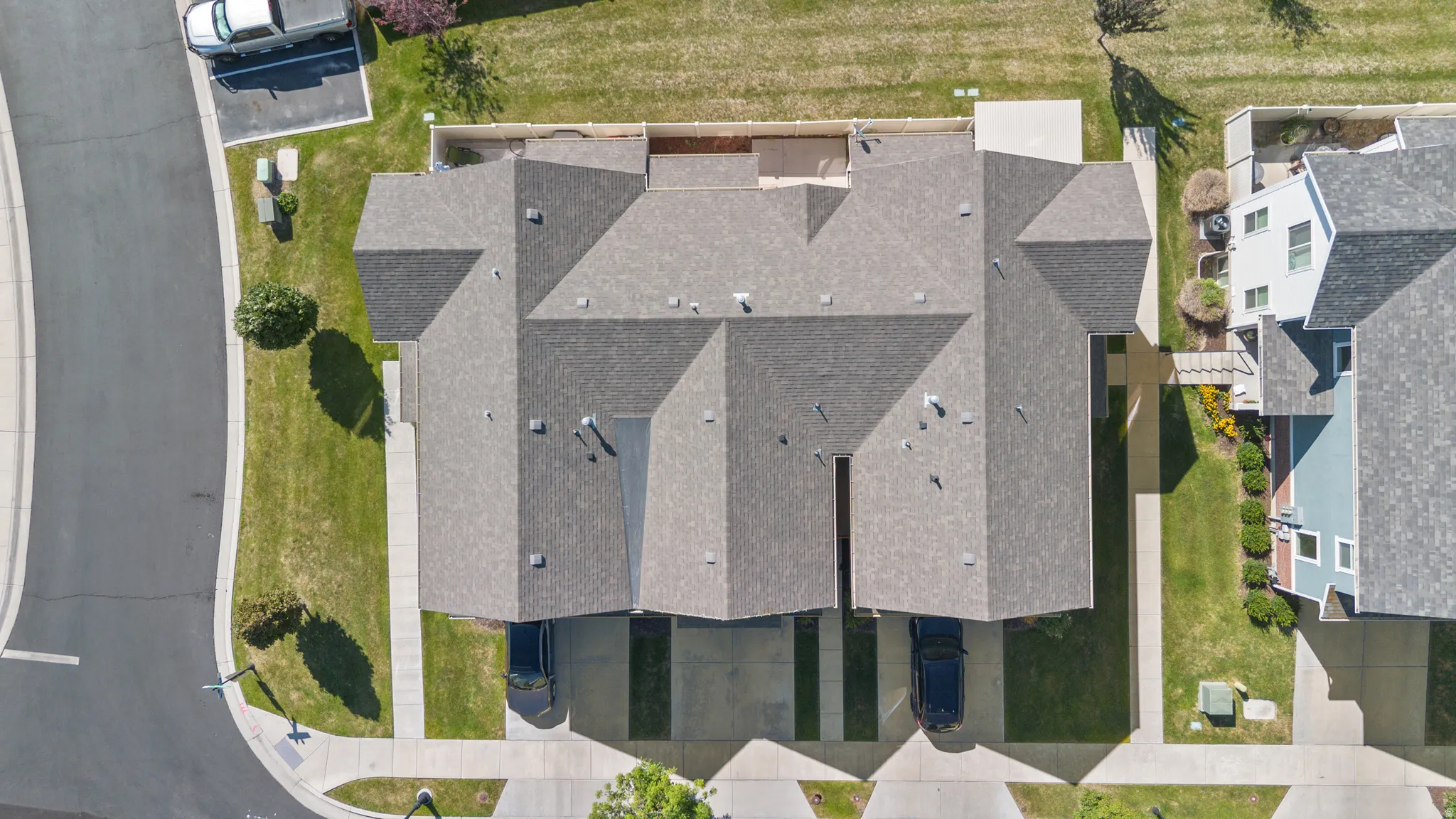 Overhead perspective highlighting two properties with gray shingled roofs and individual driveways