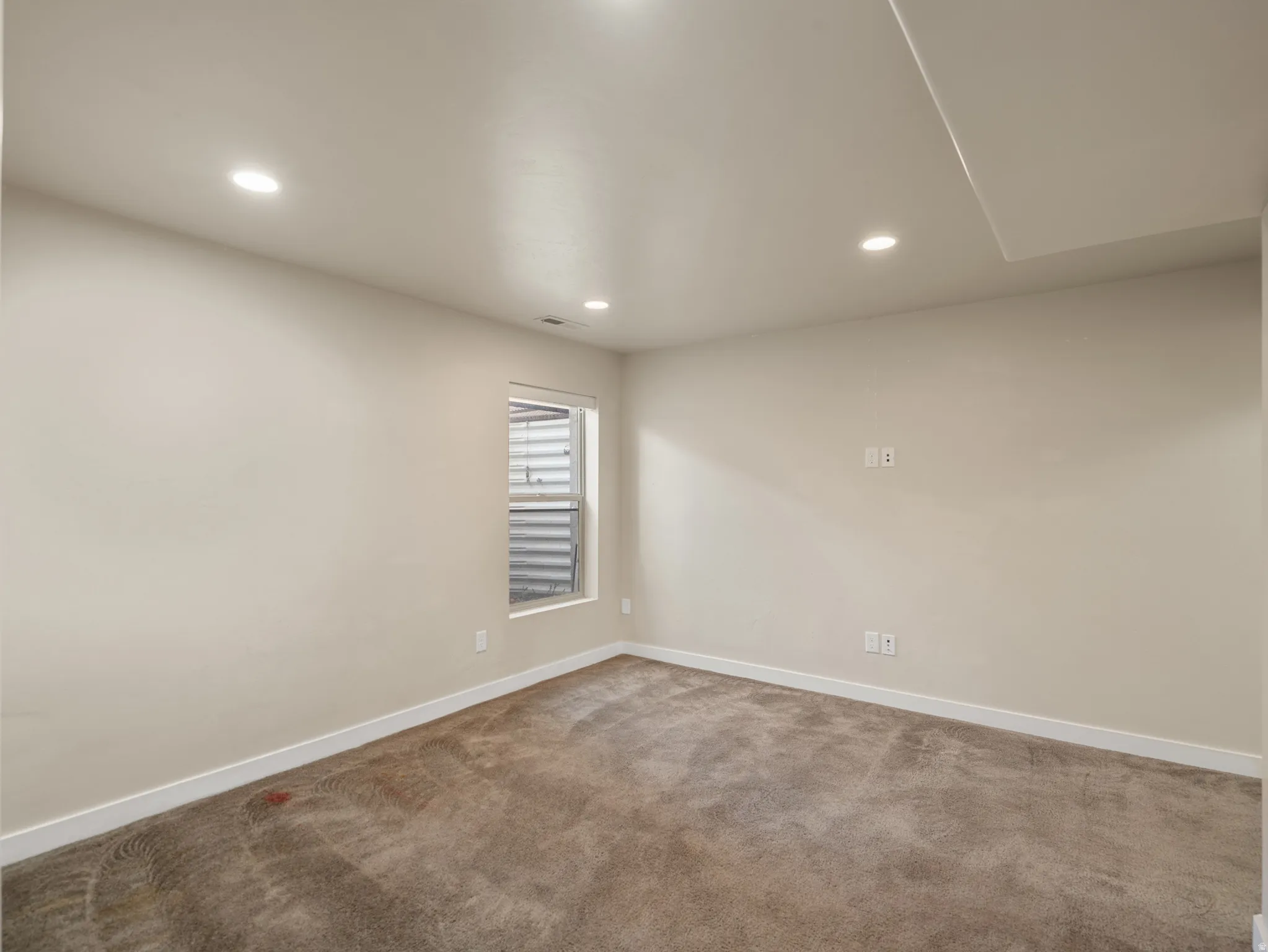 Neutral-toned wall finishes with recessed lighting and carpet flooring