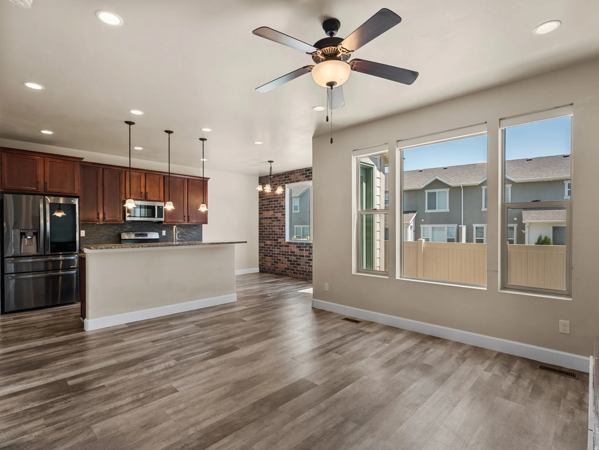 Open-concept living space featuring wood-finish flooring, recessed lighting, and a ceiling fan