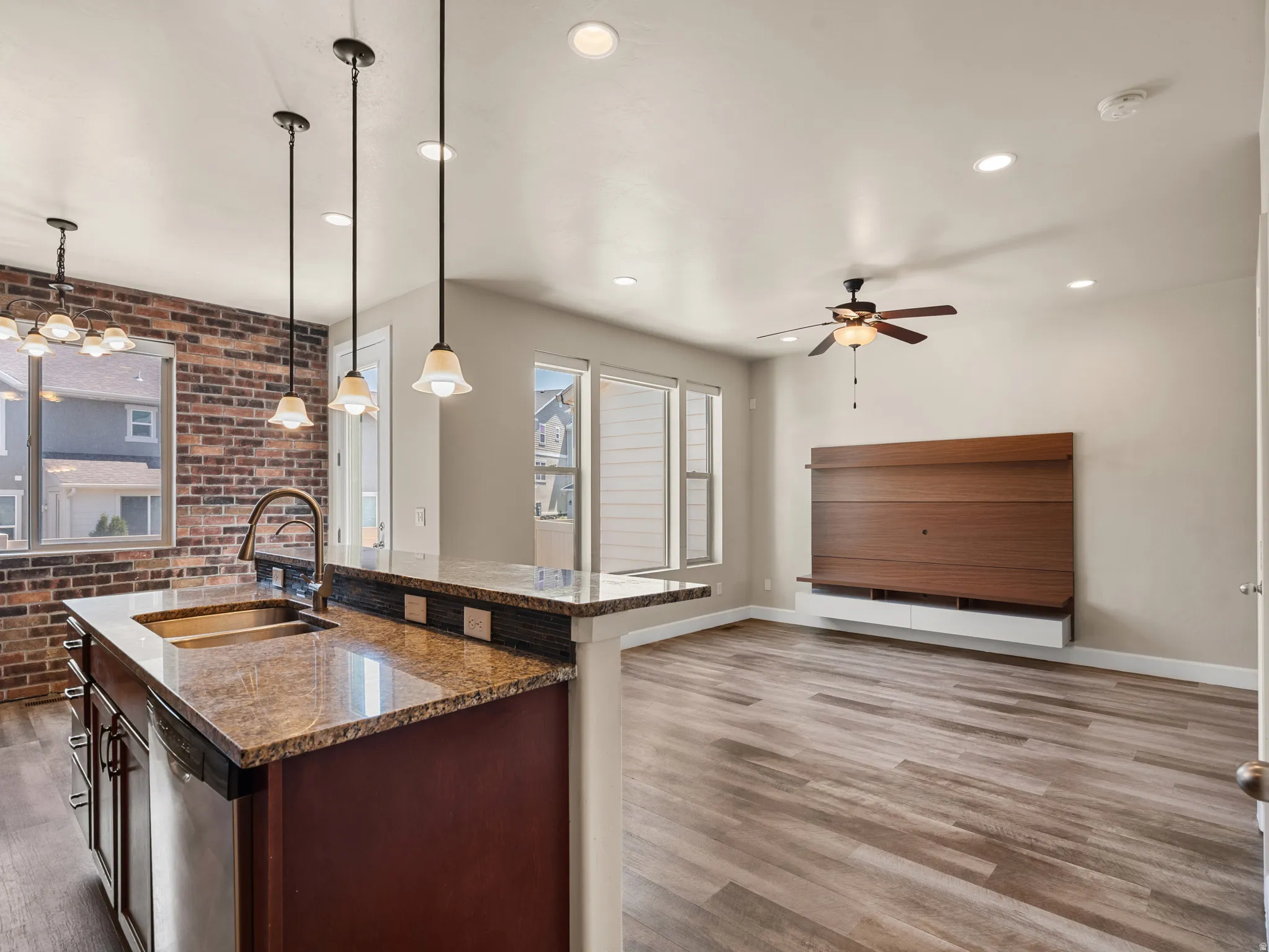 Kitchen island with granite countertop, undermount sink, and pendant lighting