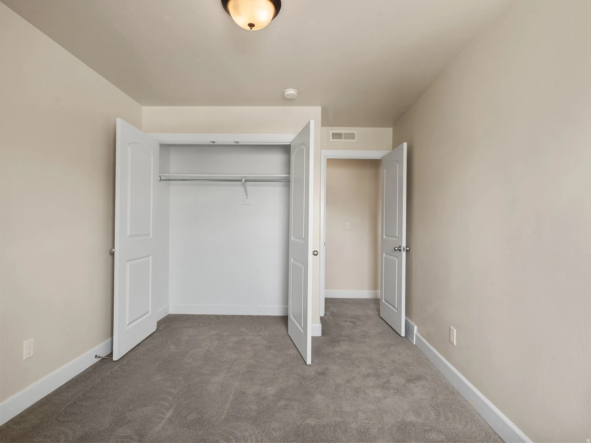 Room featuring neutral tone walls, white trim, and gray carpet flooring
