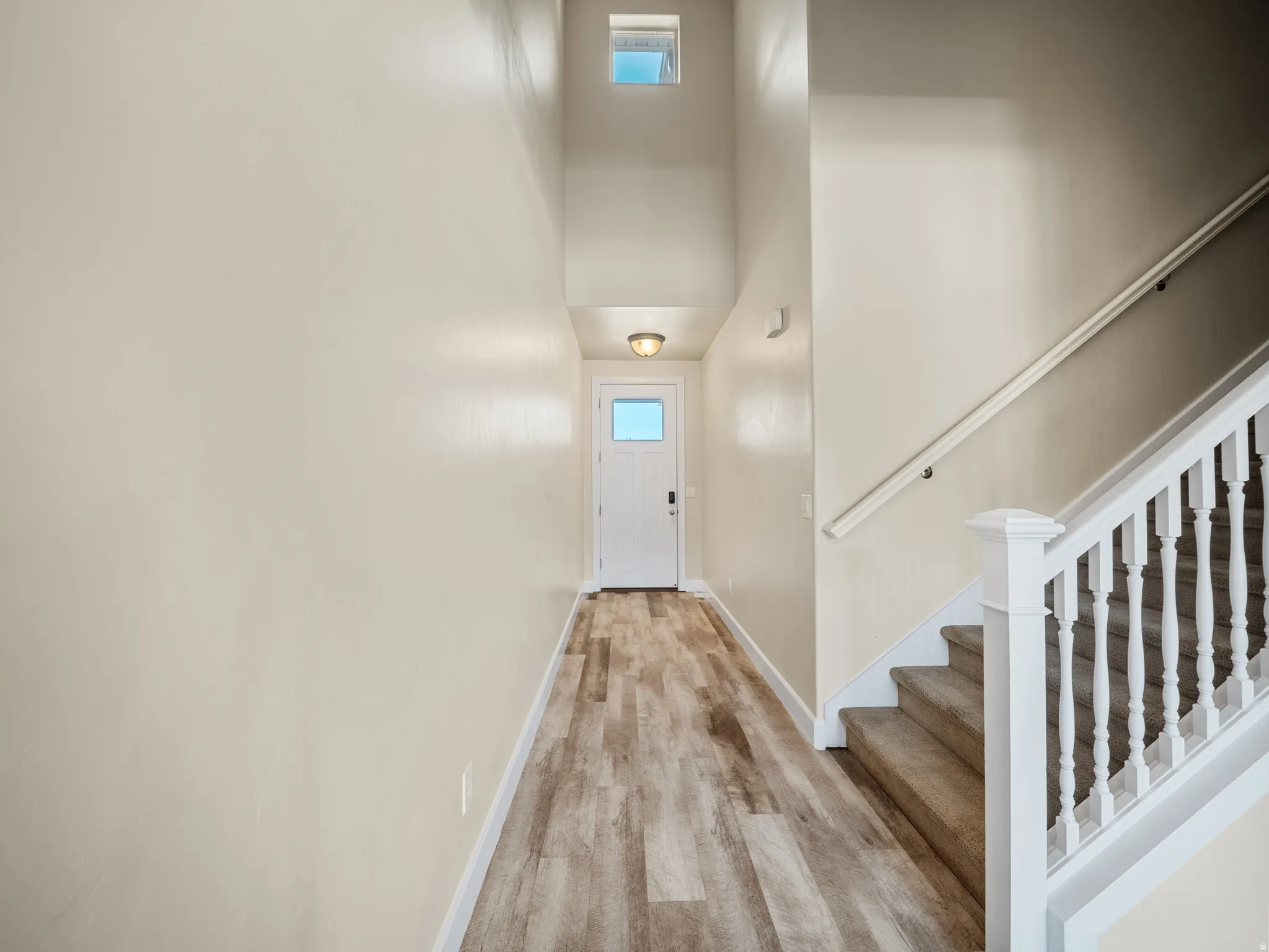 Entryway featuring wood-finish flooring, a contemporary ceiling light fixture, and a white paneled door with a rectangular window