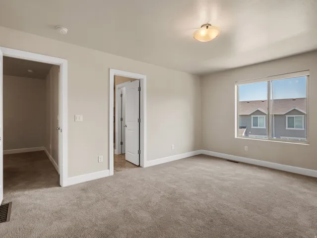 Spacious room featuring neutral carpeting, a large window, and light-toned walls
