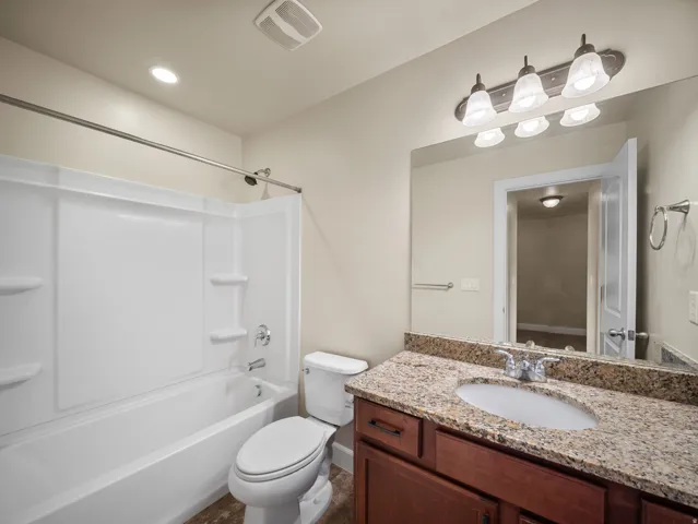 Spa-inspired master bathroom featuring a granite-topped vanity with dual sink basins, rich wood cabinetry, and polished chrome hardware