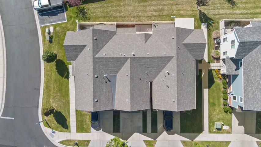 Overhead perspective highlighting two properties with gray shingled roofs and individual driveways