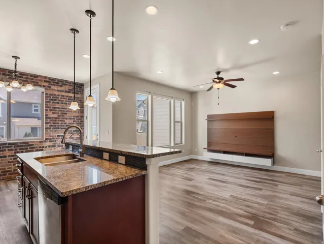 Kitchen island with granite countertop, undermount sink, and pendant lighting