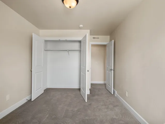 Room featuring neutral tone walls, white trim, and gray carpet flooring