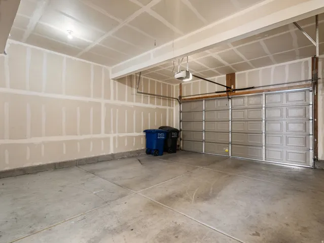 Spacious garage featuring a concrete floor, automatic garage door opener, and unfinished drywall walls