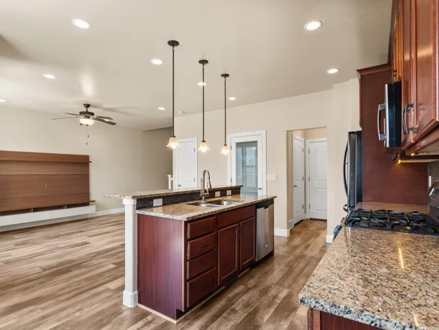 Kitchen island with granite countertop, integrated sink, and stainless steel dishwasher