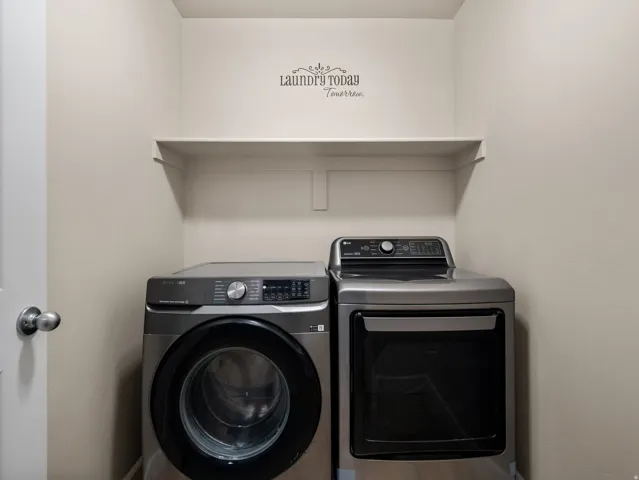 Dedicated laundry area featuring a built-in shelving unit, neutral wall color, and a standard door with a polished chrome knob