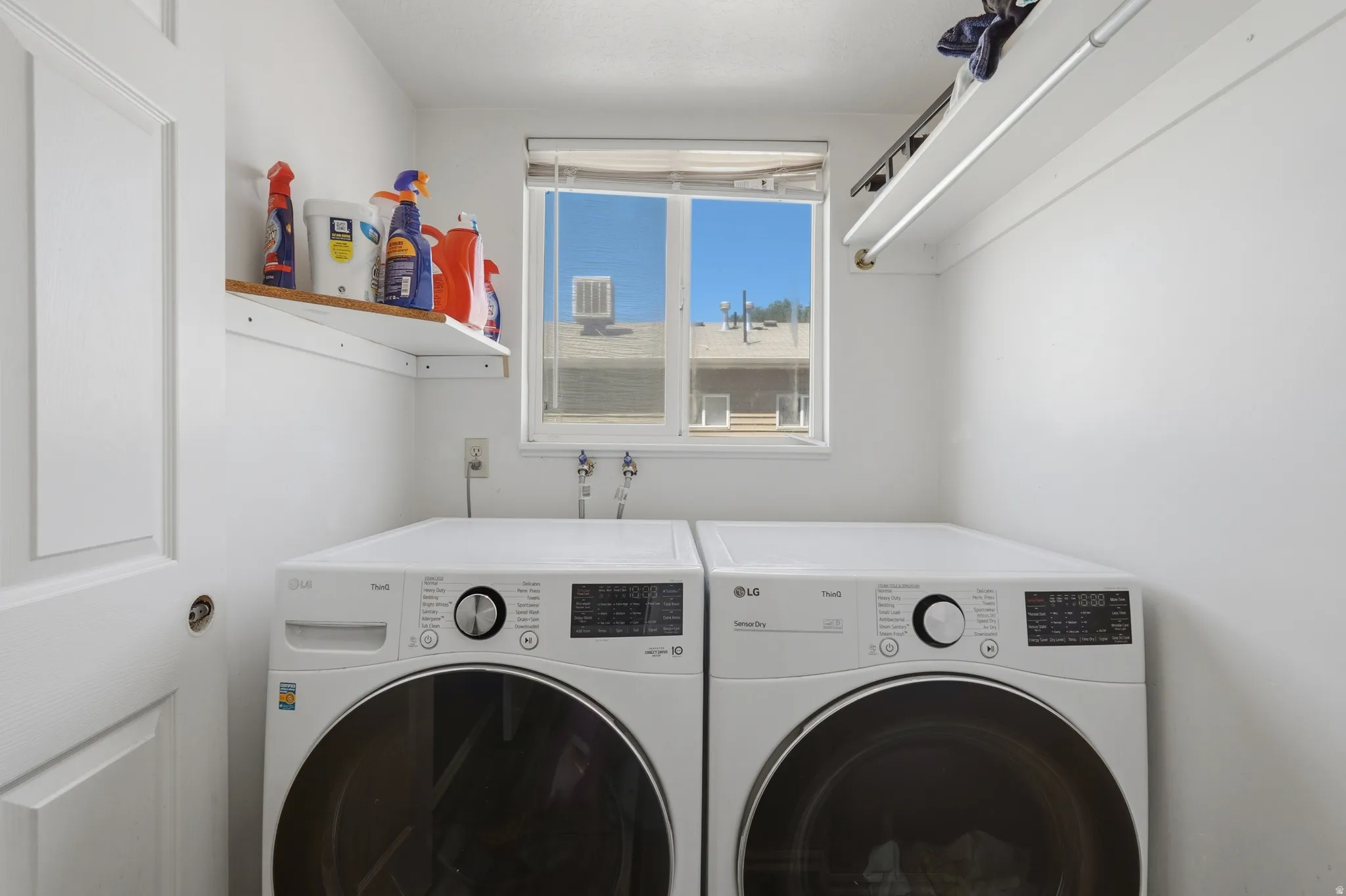 Dedicated laundry area featuring a window, built-in shelving, and a clothing rod