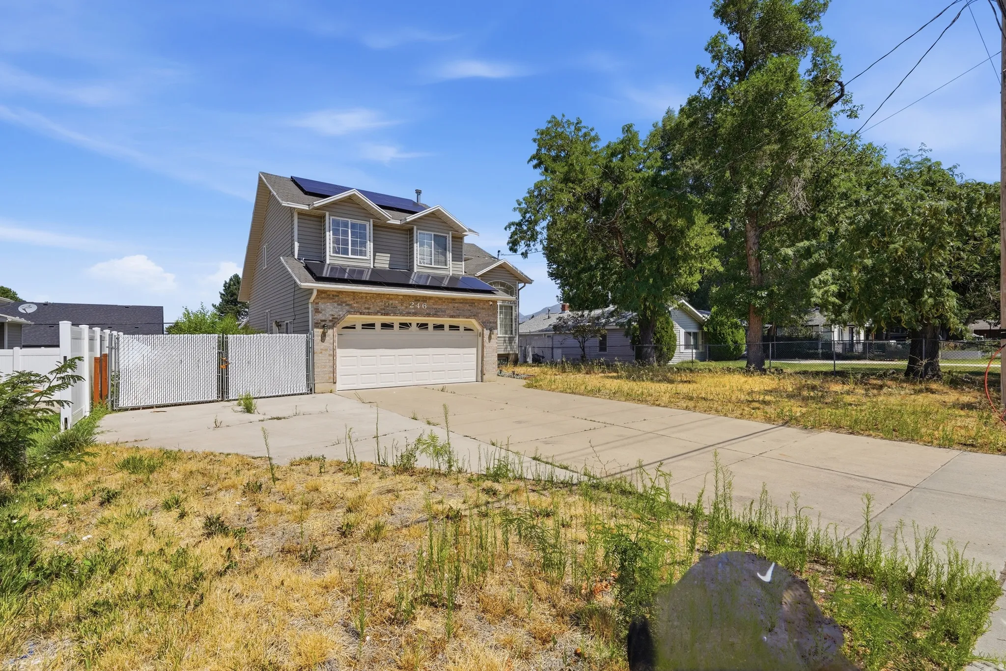 Tri Level residence featuring siding and stone facade, solar panels, and a two-car garage