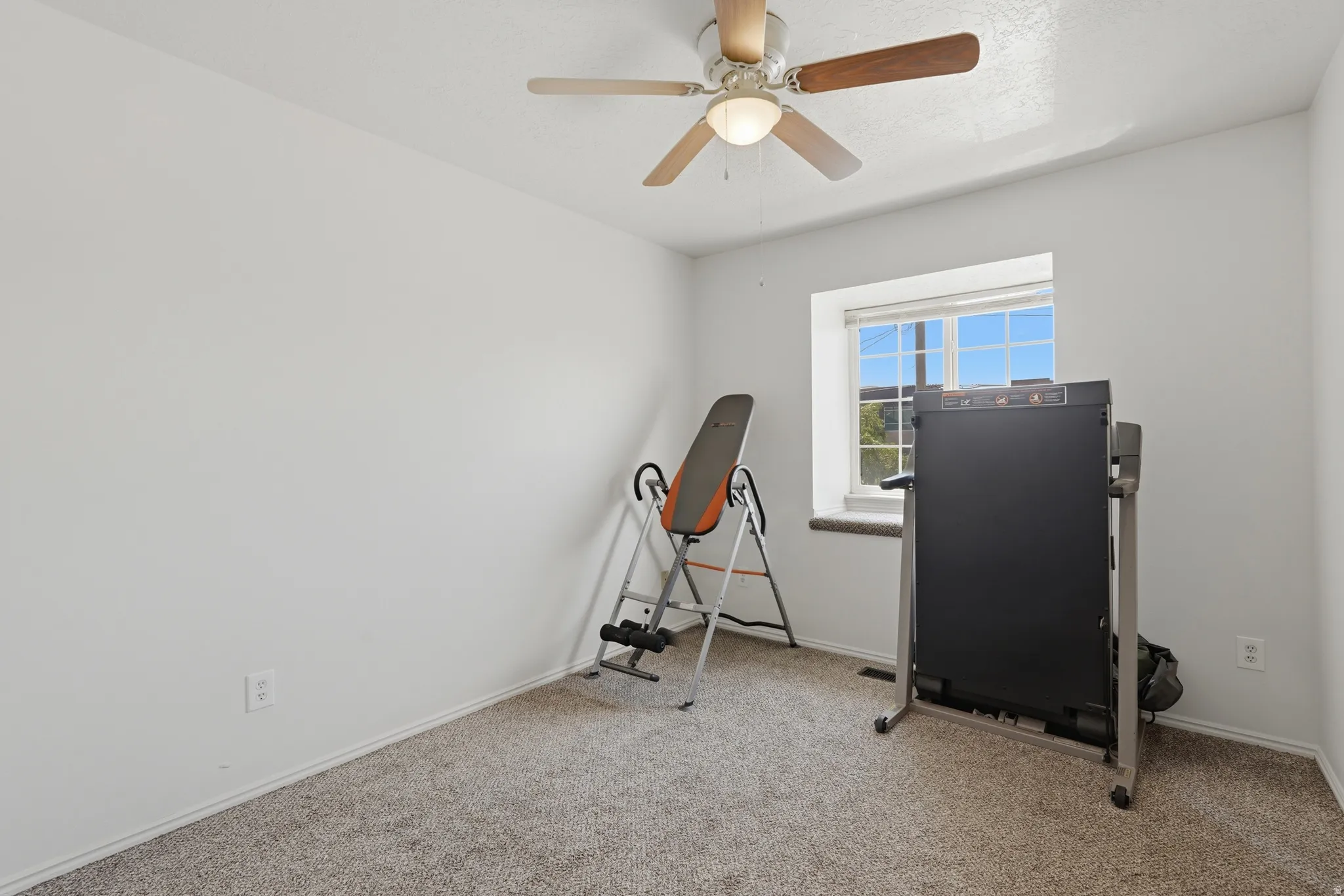 Carpeted room featuring a ceiling fan with integrated lighting, a window with horizontal blinds, and white baseboards