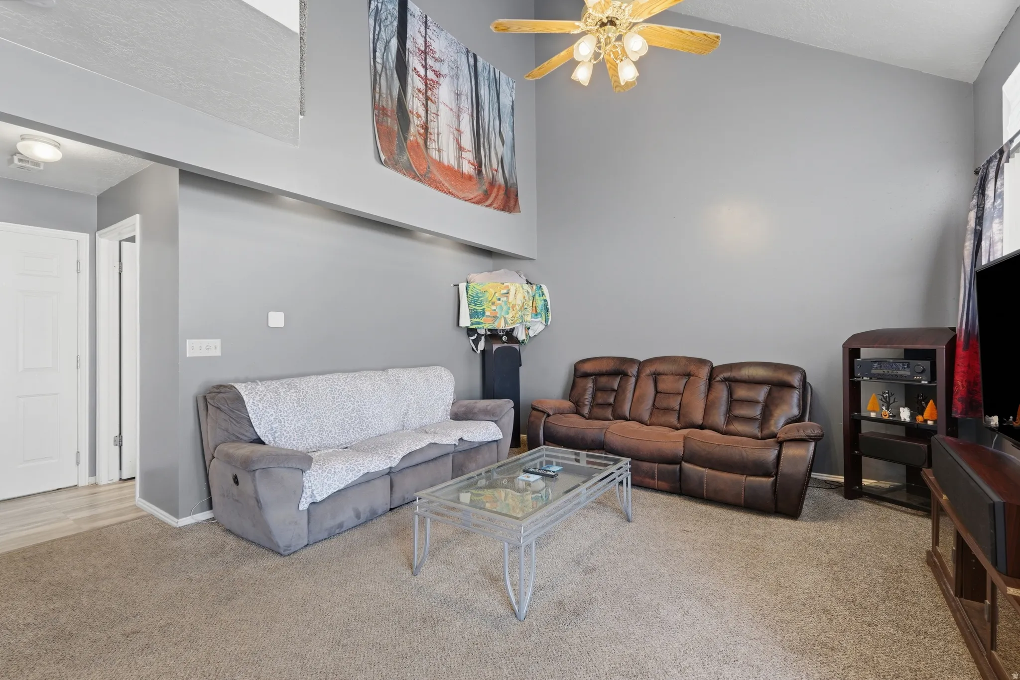 Spacious living area featuring a gray upholstered reclining sofa, brown leather reclining sectional, and glass-top coffee table