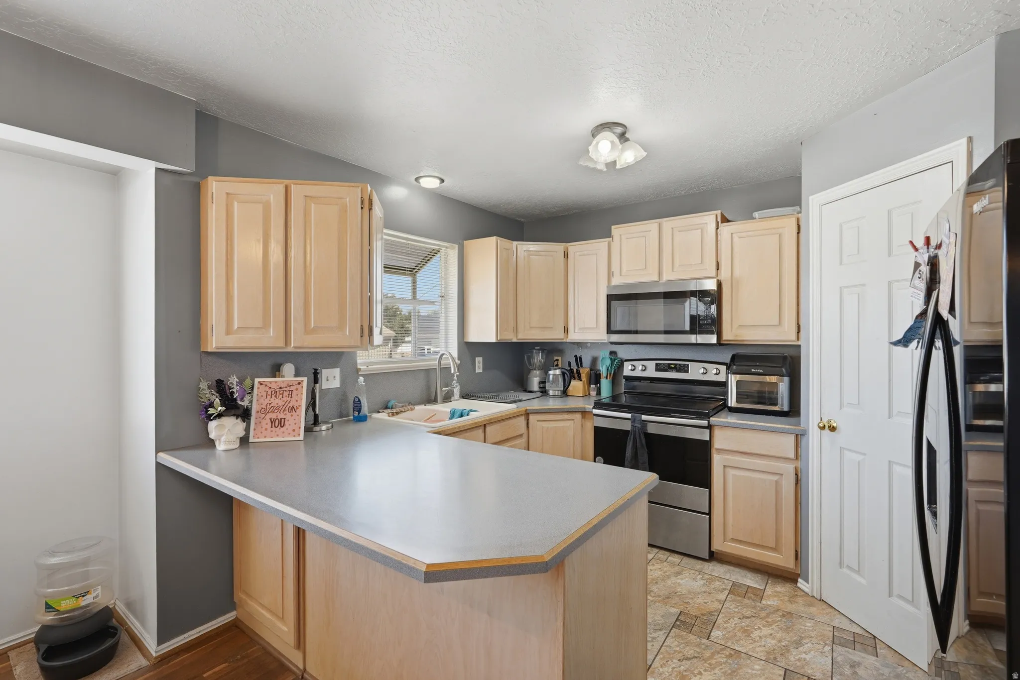 Bright and functional kitchen featuring natural wood cabinetry, stainless steel appliances, and a generous island with gray quartz countertops