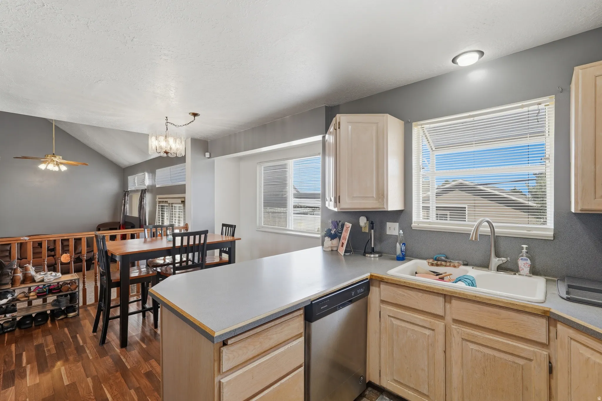 Kitchen featuring light wood-finish cabinetry, a stainless steel dishwasher, and a double basin sink