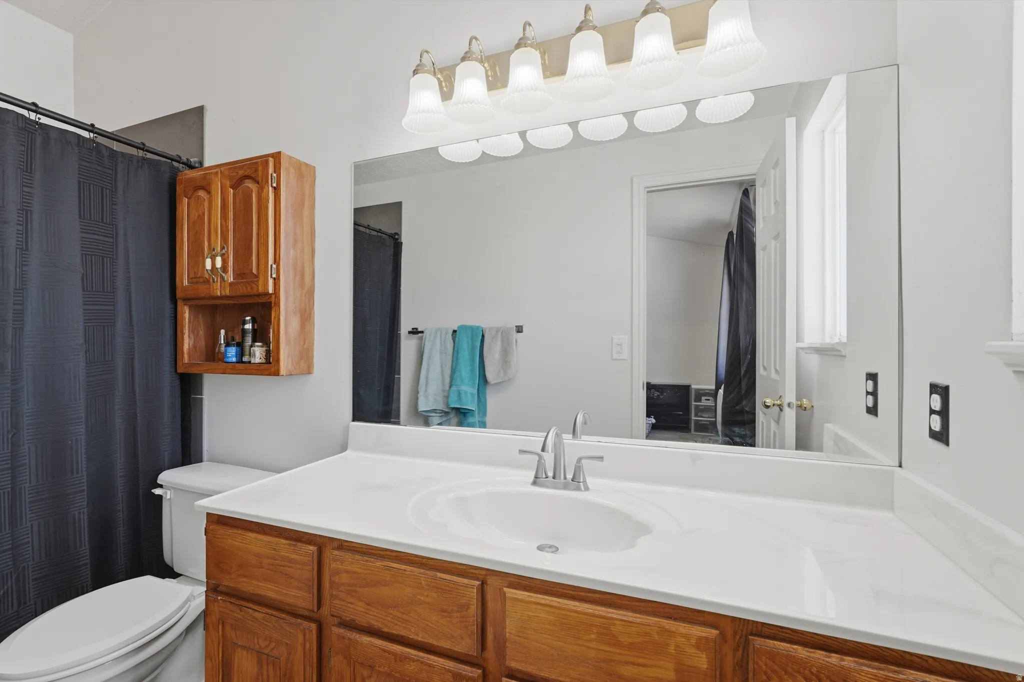 Spa-inspired primary bathroom featuring a spacious vanity with wood cabinetry, white solid-surface countertop, and chrome fixtures