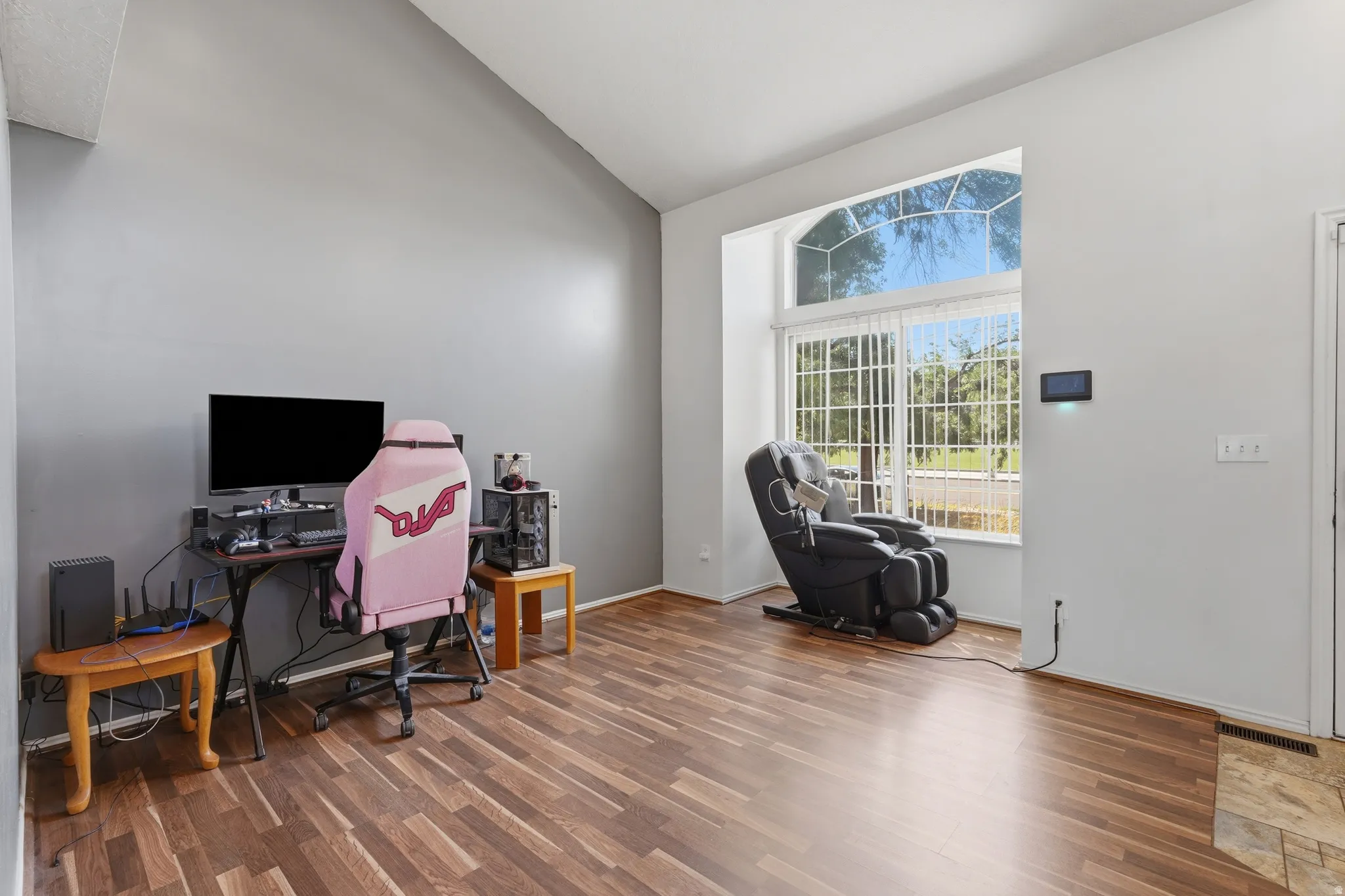 Versatile room with warm wood-finish flooring, abundant natural light from French doors and transom windows, and flexible layout ideal for home office, recreation, or fitness space