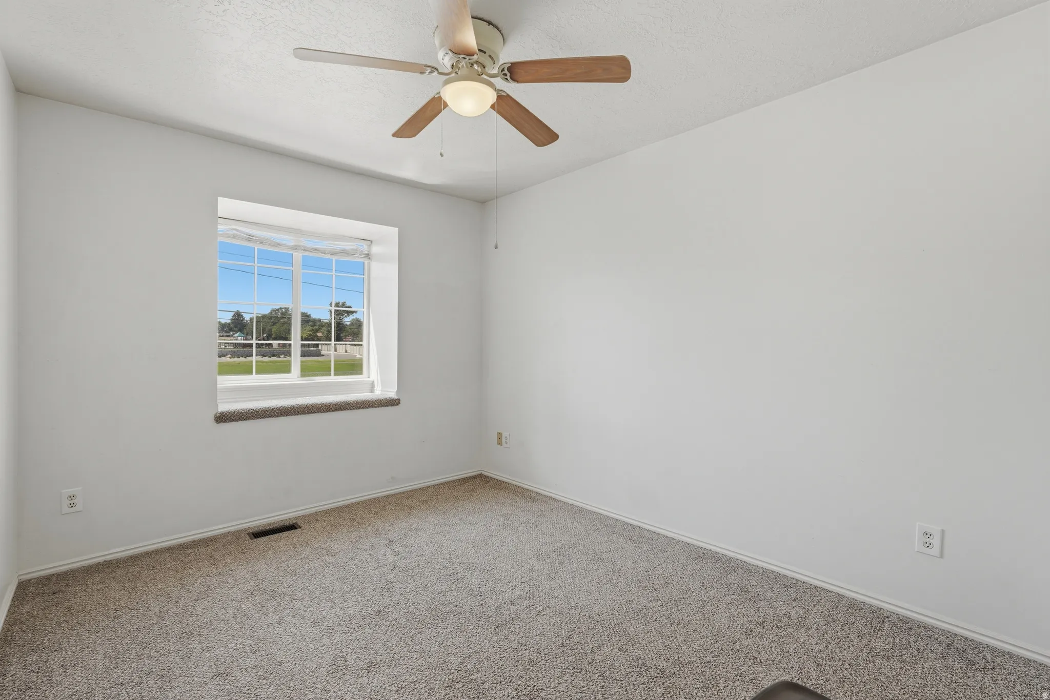 Carpeted room with a ceiling fan, a window with a sill, and white walls