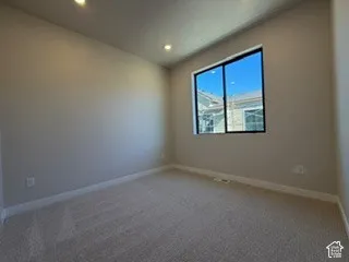 Neutral-toned carpeted room featuring recessed lighting and a large sliding window