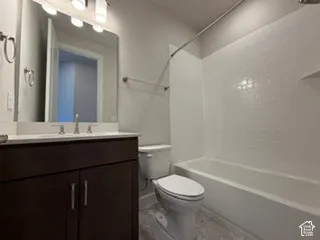 Bathroom featuring a dark wood-finish vanity with a light-toned countertop, subway tile shower surround, and multi-bulb light fixture above the vanity mirror