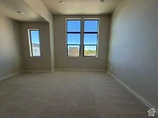 Neutral-toned interior featuring high ceilings, carpeted flooring, and oversized windows with dark-finish framing and recessed lighting