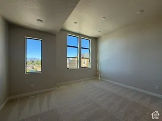 Interior space featuring neutral-toned carpeting, high ceilings, recessed lighting, and multiple windows with mountain and neighborhood scenery