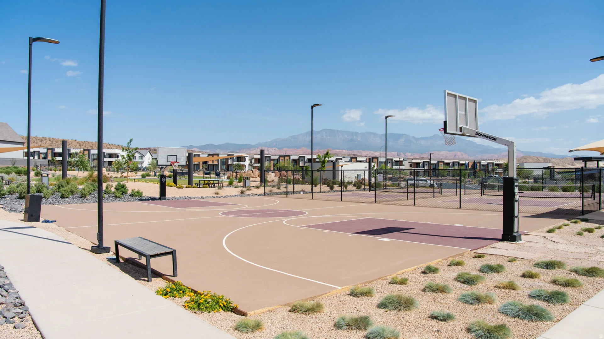 Outdoor multi-sport court featuring a basketball hoop, perimeter fencing, and adjacent pickleball courts