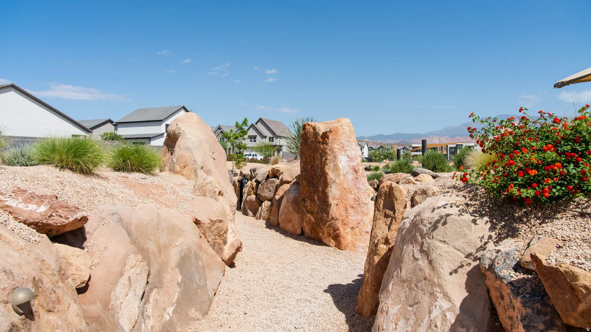Desert-inspired landscaping featuring a gravel pathway bordered by large natural rock formations