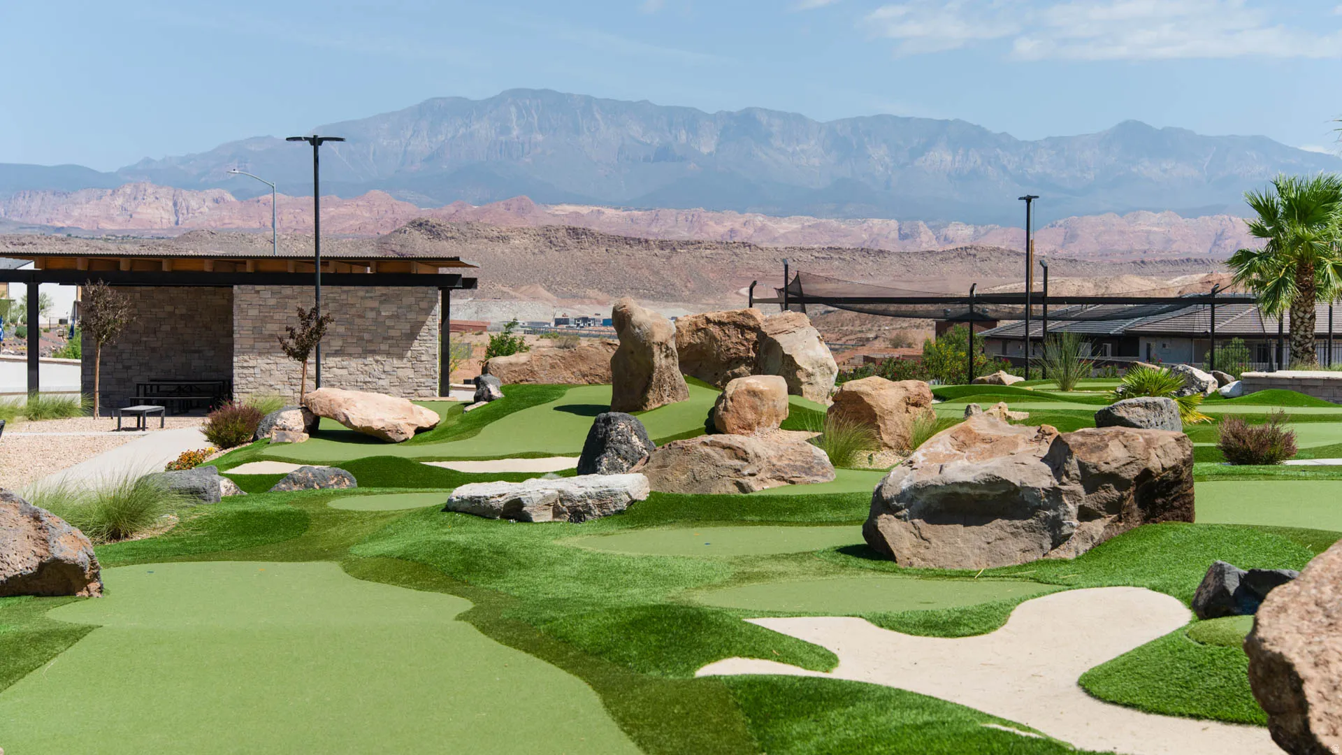 Mini golf course featuring artificial turf, sand traps, and large decorative boulders