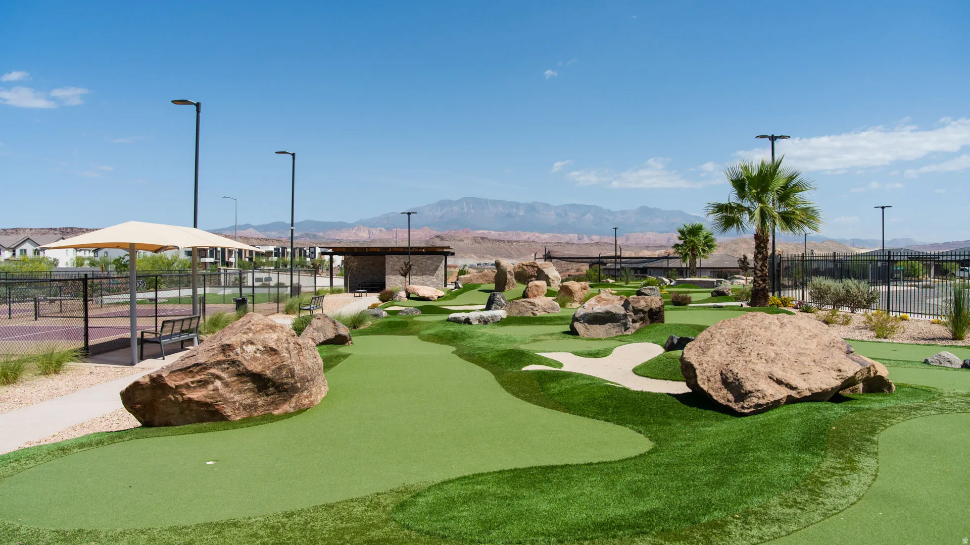 Miniature golf course featuring varied green turf, natural rock formations, and a sand trap