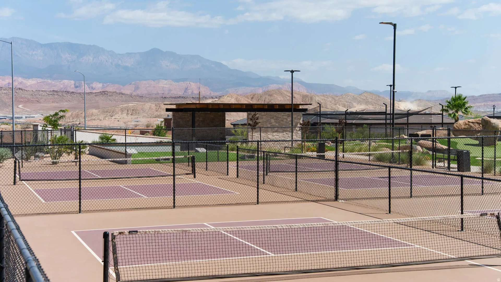 Multiple pickleball courts with perimeter fencing and integrated lighting