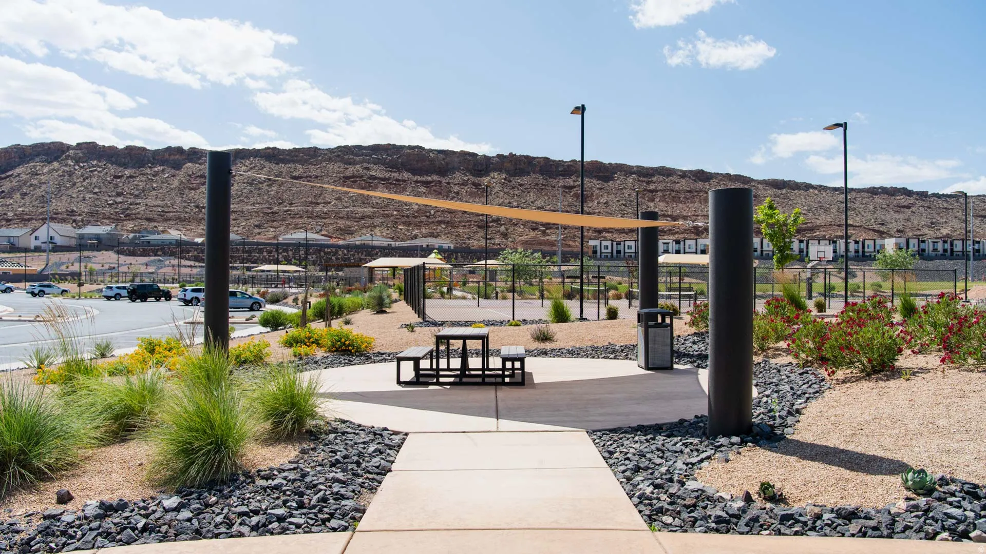 Outdoor amenity area featuring a shade sail, picnic seating, and desert landscaping