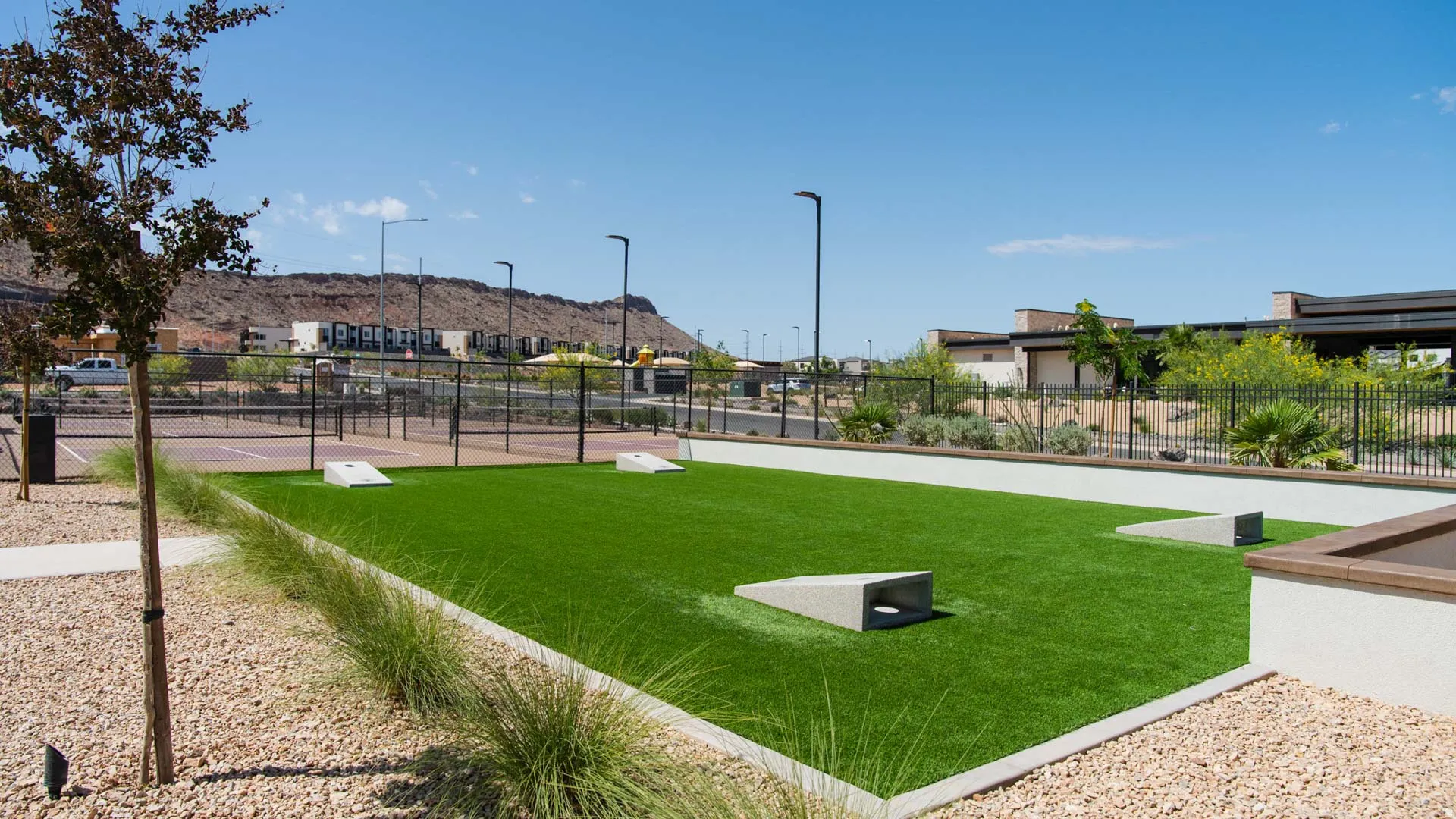 Expansive recreational lawn featuring professionally maintained turf, modern hardscape pathways in concrete, and mature landscaping with ornamental grasses and trees