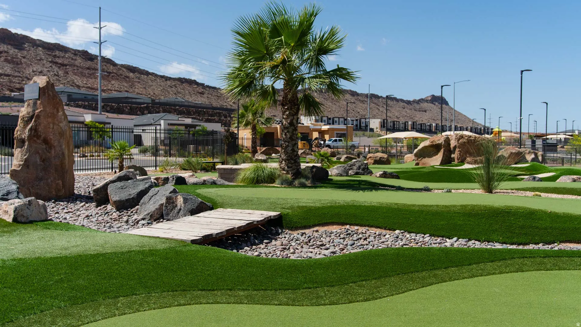 Beautifully landscaped grounds featuring lush turf, mature palm tree, decorative rock accents, and stone pathway elements