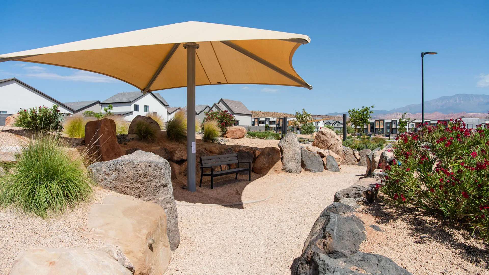 Desert Landscape with Shade Structure and Seating AreaThis outdoor space features a striking cantilever shade structure with a tan fabric canopy providing protection from the elements