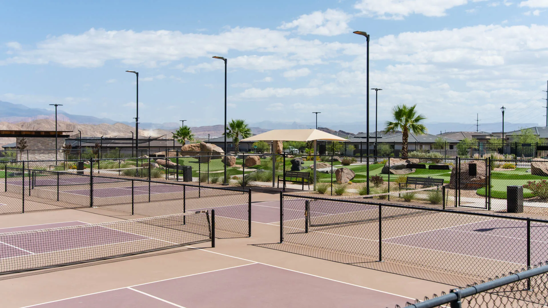 Multiple pickleball courts with perimeter fencing, illuminated by modern light poles
