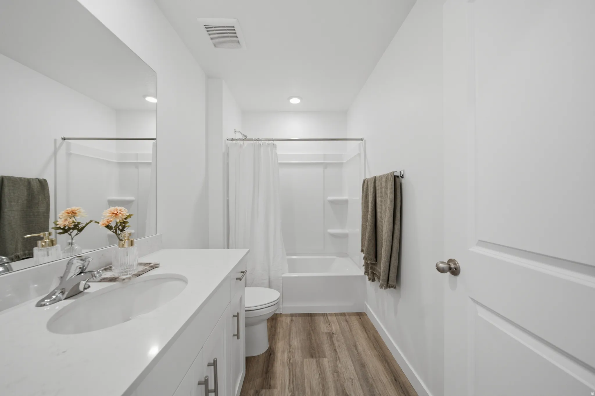 Modern primary bathroom featuring a long vanity with dual sinks, white quartz countertop, and polished chrome fixtures