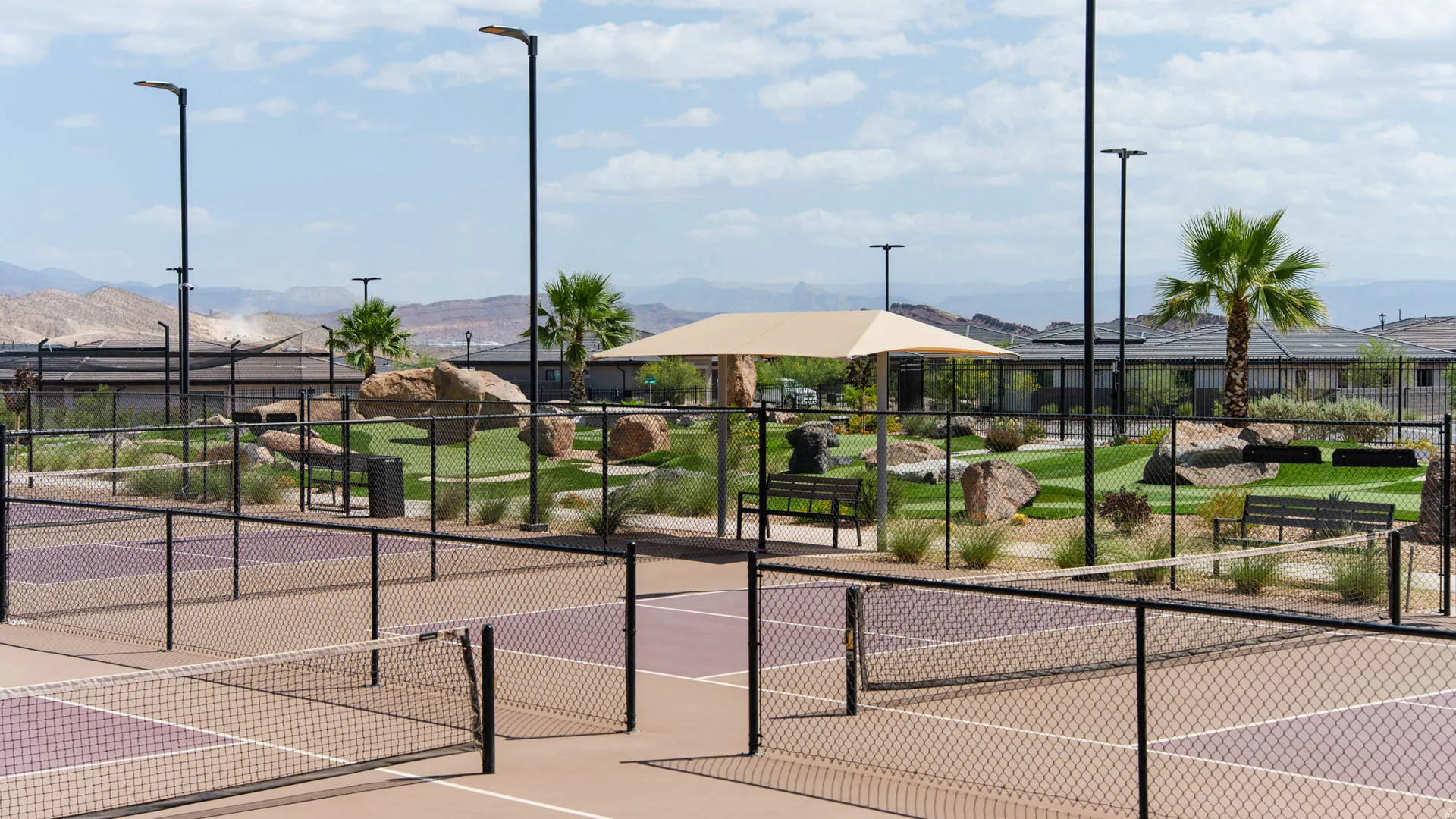 Premier recreational facilities featuring multiple professional-grade tennis courts with championship-surface flooring, surrounded by manicured landscaping with mature palm trees and native plantings