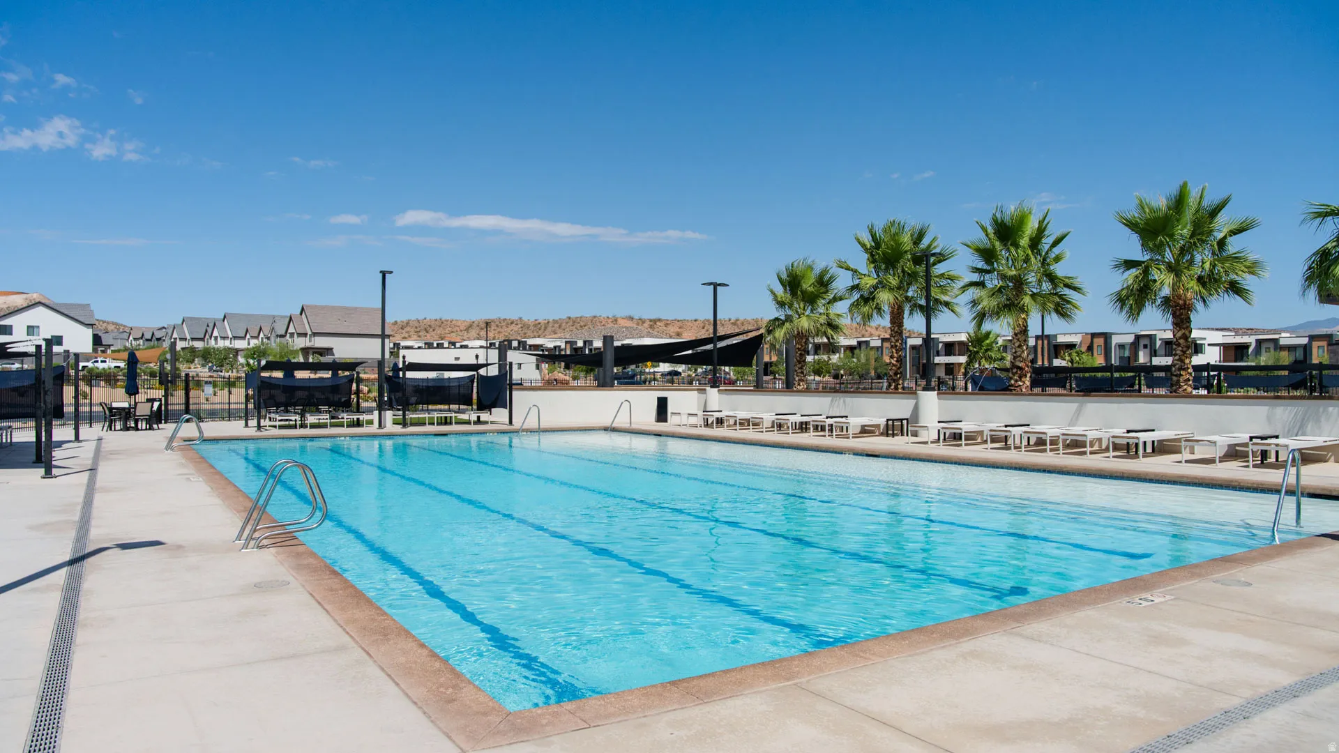 Resort-style Olympic-length lap pool featuring crystal-clear water, multiple lane markings, and surrounding concrete decking