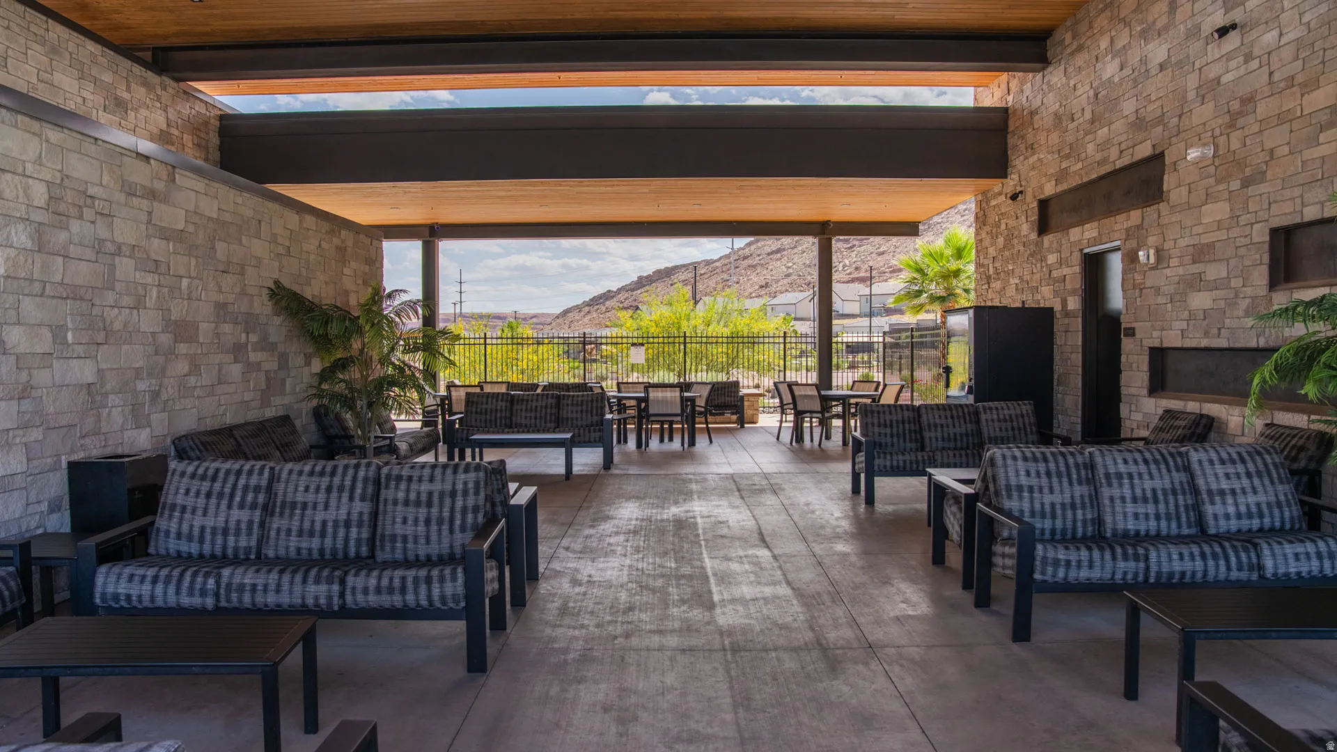 Spacious outdoor lounge area featuring stone-clad walls and a wood-paneled ceiling