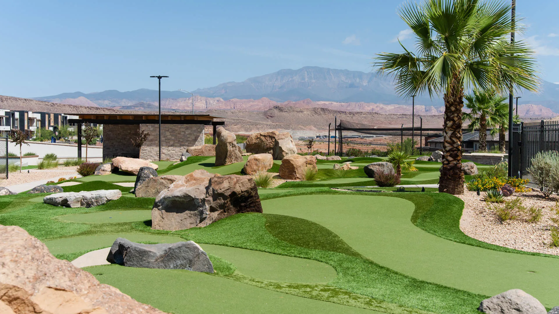 Putting green with artificial turf, bordered by natural rock landscaping and desert plantings