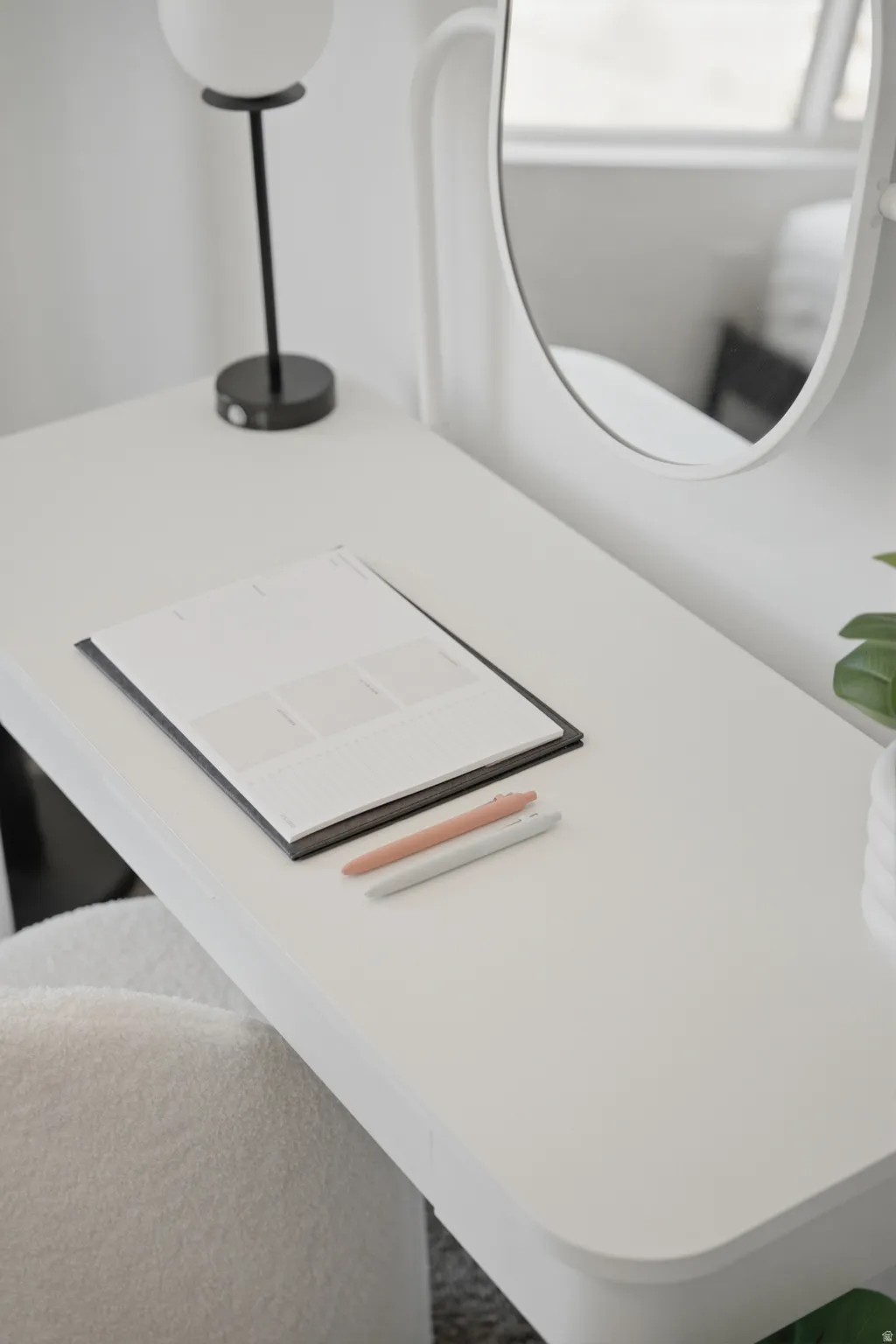 White desk with a curved mirror, spherical light fixture, and plush seating