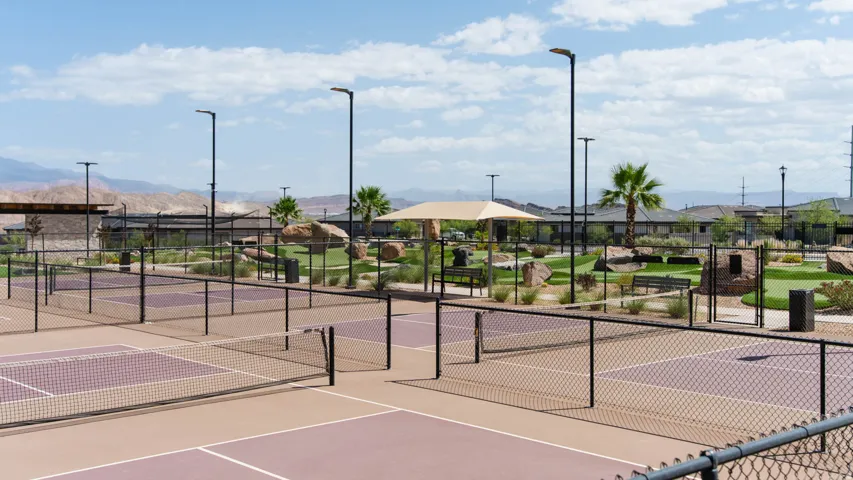 Multiple pickleball courts with perimeter fencing, illuminated by modern light poles