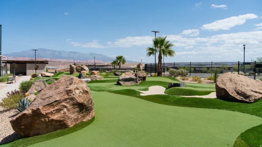 Putting green featuring artificial turf, integrated sand traps, and natural rock landscaping